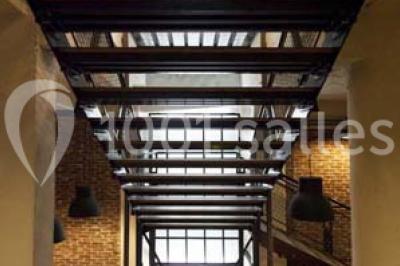 Salle de conférence vide avec des rangées de chaises en bois, un écran de projection et des tableaux accrochés au mur.