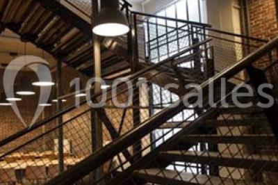 Salle de conférence vide avec des rangées de chaises en bois, un écran de projection et des tableaux accrochés au mur.