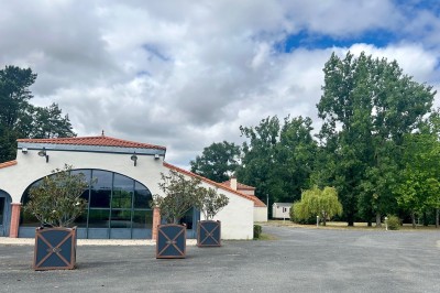 Mobil-home avec terrasse en bois, situé sur une pelouse, entouré d'arbres et partiellement ombragé.