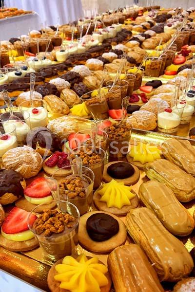 Plateau de desserts variés comprenant éclairs, tartelettes, verrines et pâtisseries colorées disposées en rangées.
