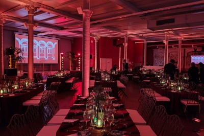 Salle de conférence vide avec rangées de sièges rouges, écran de projection et éclairage fluorescent.
