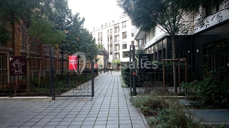 Entrée d'une voie privée bordée de végétation, avec des panneaux d'information et des bâtiments en arrière-plan.