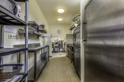 Armoire en bois ouverte contenant des verres, assiettes, bols et carafes, organisée sur plusieurs étagères.