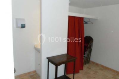 Armoire en bois ouverte contenant des verres, assiettes, bols et carafes, organisée sur plusieurs étagères.