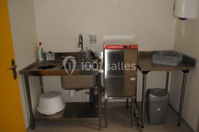 Armoire en bois ouverte contenant des verres, assiettes, bols et carafes, organisée sur plusieurs étagères.