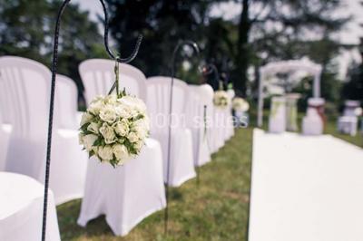 Un jardin verdoyant avec pelouse, arbustes et grands arbres, devant une tour en pierre sous un ciel légèrement nuageux.