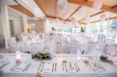 Un jardin verdoyant avec pelouse, arbustes et grands arbres, devant une tour en pierre sous un ciel légèrement nuageux.