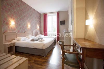 Un jardin verdoyant avec pelouse, arbustes et grands arbres, devant une tour en pierre sous un ciel légèrement nuageux.