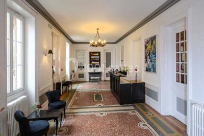 Un jardin verdoyant avec pelouse, arbustes et grands arbres, devant une tour en pierre sous un ciel légèrement nuageux.