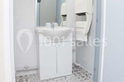 Un jardin verdoyant avec pelouse, arbustes et grands arbres, devant une tour en pierre sous un ciel légèrement nuageux.