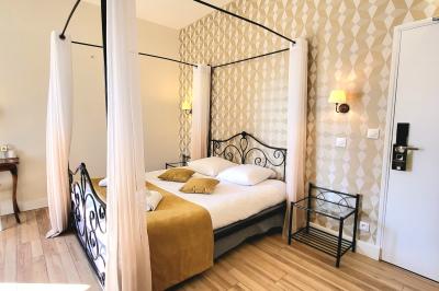 Un jardin verdoyant avec pelouse, arbustes et grands arbres, devant une tour en pierre sous un ciel légèrement nuageux.