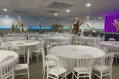 Salle de réception avec bar éclairé par des lumières colorées et invités rassemblés dans une ambiance tamisée.
