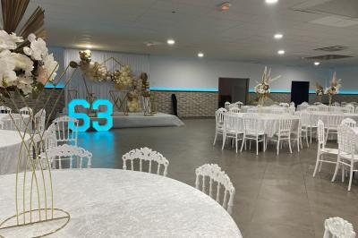 Salle de réception avec bar éclairé par des lumières colorées et invités rassemblés dans une ambiance tamisée.