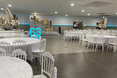 Salle de réception avec bar éclairé par des lumières colorées et invités rassemblés dans une ambiance tamisée.