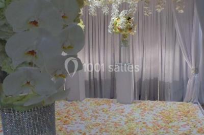 Salle de réception avec bar éclairé par des lumières colorées et invités rassemblés dans une ambiance tamisée.