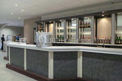 Salle de réception avec bar éclairé par des lumières colorées et invités rassemblés dans une ambiance tamisée.