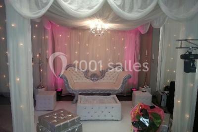 Salle de réception avec bar éclairé par des lumières colorées et invités rassemblés dans une ambiance tamisée.