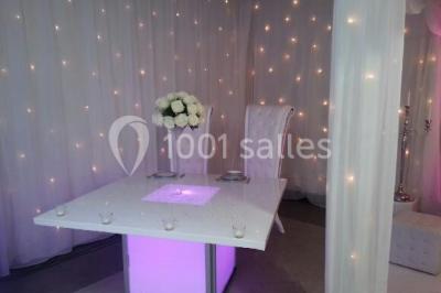 Salle de réception avec bar éclairé par des lumières colorées et invités rassemblés dans une ambiance tamisée.