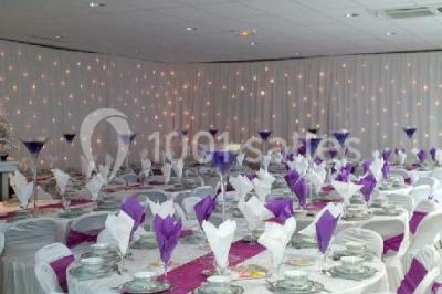 Salle de réception avec bar éclairé par des lumières colorées et invités rassemblés dans une ambiance tamisée.