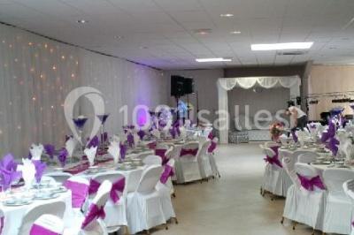 Salle de réception avec bar éclairé par des lumières colorées et invités rassemblés dans une ambiance tamisée.