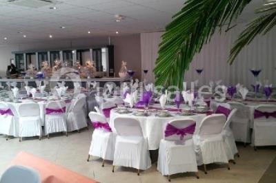 Salle de réception avec bar éclairé par des lumières colorées et invités rassemblés dans une ambiance tamisée.