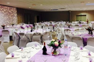 Salle de réception avec bar éclairé par des lumières colorées et invités rassemblés dans une ambiance tamisée.
