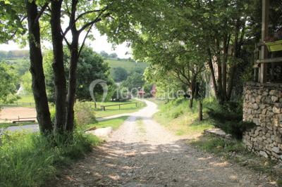 Tente tipi beige installée dans un champ verdoyant sous un ciel bleu, avec une ouverture laissant entrevoir l'intérieur.