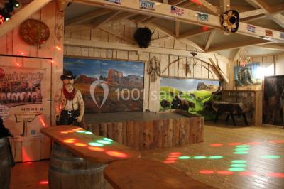 Tente tipi beige installée dans un champ verdoyant sous un ciel bleu, avec une ouverture laissant entrevoir l'intérieur.