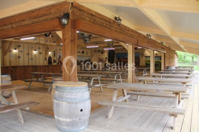 Tente tipi beige installée dans un champ verdoyant sous un ciel bleu, avec une ouverture laissant entrevoir l'intérieur.