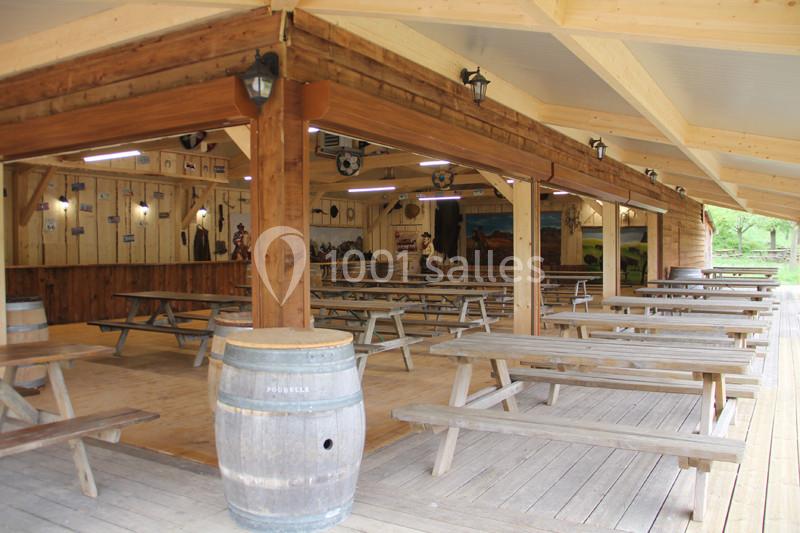 Abri en bois avec tables de pique-nique, tonneau décoratif et murs ornés de peintures dans un cadre rustique.