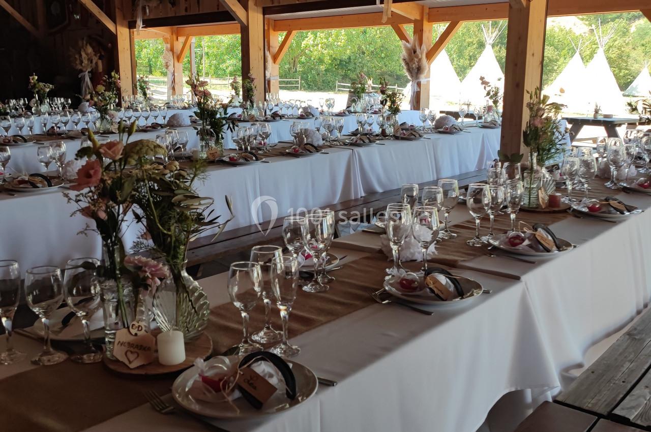 Tables décorées pour un mariage ou un événement, avec nappes blanches, vaisselle élégante et arrangements floraux.