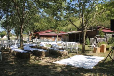 Tente tipi beige installée dans un champ verdoyant sous un ciel bleu, avec une ouverture laissant entrevoir l'intérieur.