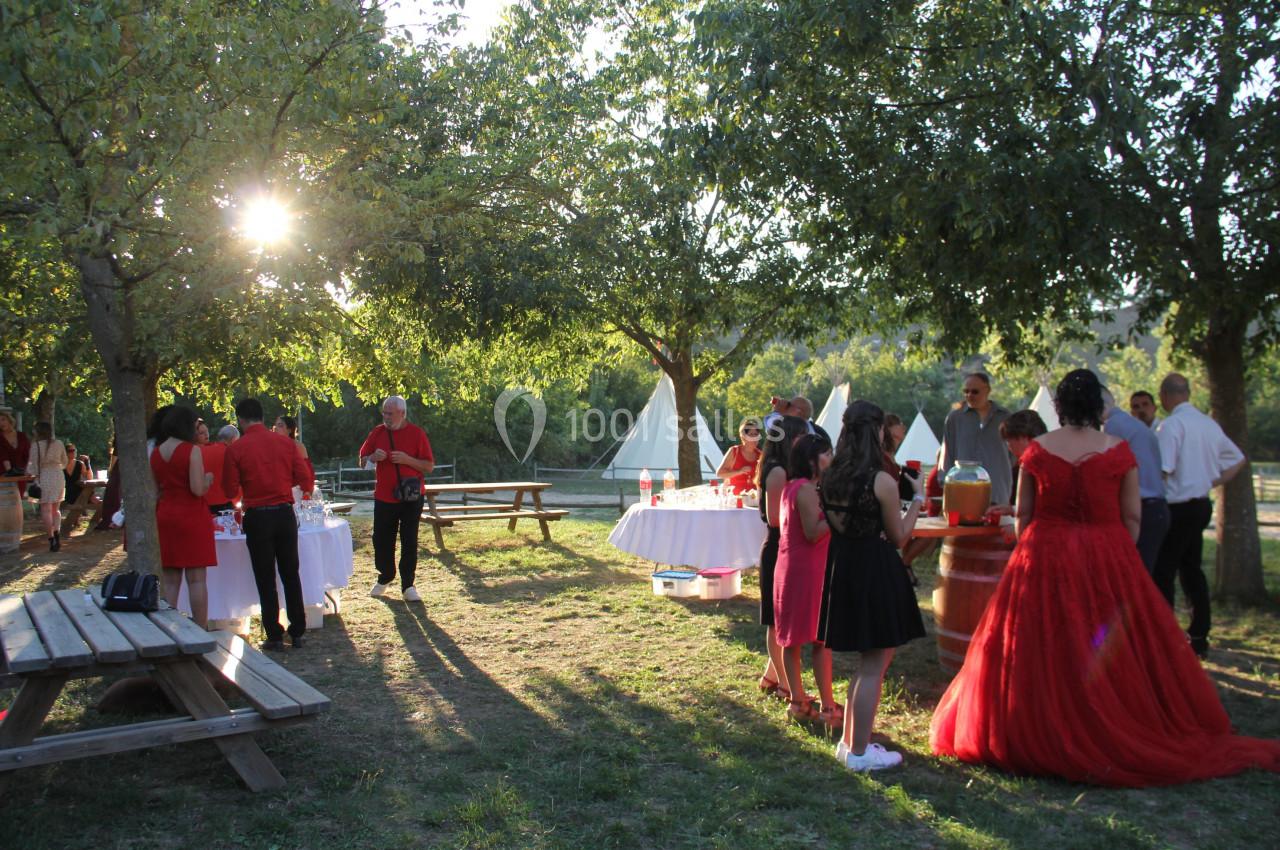 Groupe de personnes rassemblées dans un jardin ensoleillé, près de tables décorées, lors d'un événement festif.
