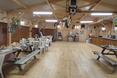 Tente tipi beige installée dans un champ verdoyant sous un ciel bleu, avec une ouverture laissant entrevoir l'intérieur.