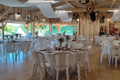 Tente tipi beige installée dans un champ verdoyant sous un ciel bleu, avec une ouverture laissant entrevoir l'intérieur.