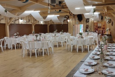 Tente tipi beige installée dans un champ verdoyant sous un ciel bleu, avec une ouverture laissant entrevoir l'intérieur.