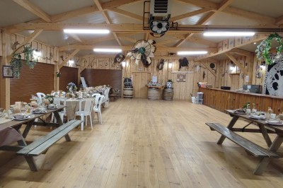 Tente tipi beige installée dans un champ verdoyant sous un ciel bleu, avec une ouverture laissant entrevoir l'intérieur.