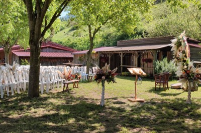 Tente tipi beige installée dans un champ verdoyant sous un ciel bleu, avec une ouverture laissant entrevoir l'intérieur.