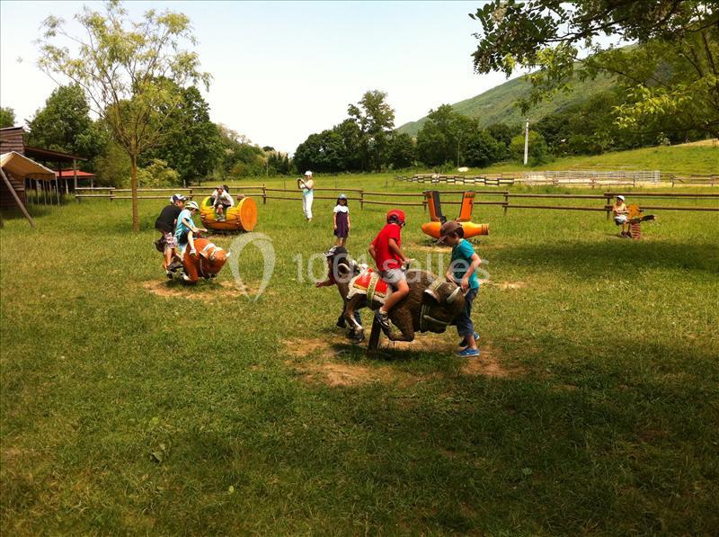 Des enfants jouent sur des structures en forme d'animaux dans un parc verdoyant par une journée ensoleillée.