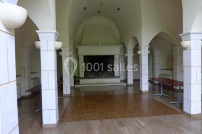 Comptoir d'accueil noir brillant dans un espace lumineux avec un sol en pierre et une plante en pot près d'une fenêtre.