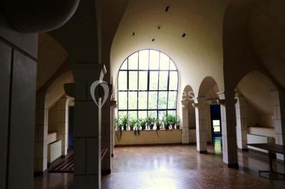 Comptoir d'accueil noir brillant dans un espace lumineux avec un sol en pierre et une plante en pot près d'une fenêtre.