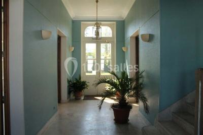 Comptoir d'accueil noir brillant dans un espace lumineux avec un sol en pierre et une plante en pot près d'une fenêtre.