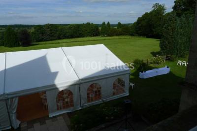Comptoir d'accueil noir brillant dans un espace lumineux avec un sol en pierre et une plante en pot près d'une fenêtre.