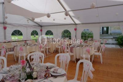 Comptoir d'accueil noir brillant dans un espace lumineux avec un sol en pierre et une plante en pot près d'une fenêtre.