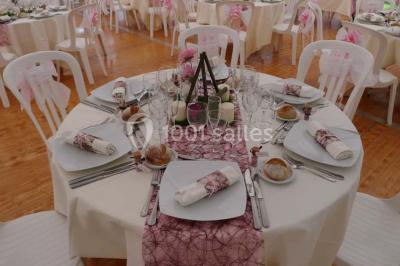 Comptoir d'accueil noir brillant dans un espace lumineux avec un sol en pierre et une plante en pot près d'une fenêtre.