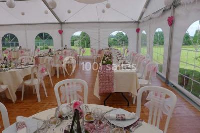 Comptoir d'accueil noir brillant dans un espace lumineux avec un sol en pierre et une plante en pot près d'une fenêtre.