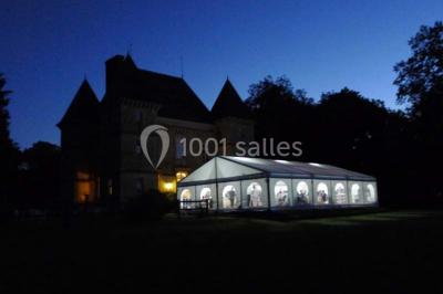 Comptoir d'accueil noir brillant dans un espace lumineux avec un sol en pierre et une plante en pot près d'une fenêtre.