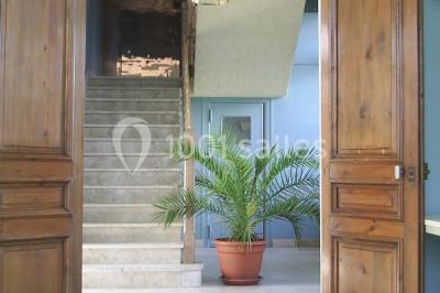 Comptoir d'accueil noir brillant dans un espace lumineux avec un sol en pierre et une plante en pot près d'une fenêtre.