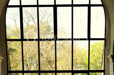 Comptoir d'accueil noir brillant dans un espace lumineux avec un sol en pierre et une plante en pot près d'une fenêtre.