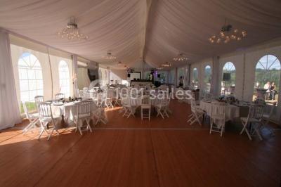 Lavabo avec plan en bois, sèche-serviettes mural, douche avec paroi vitrée et carrelage sombre.